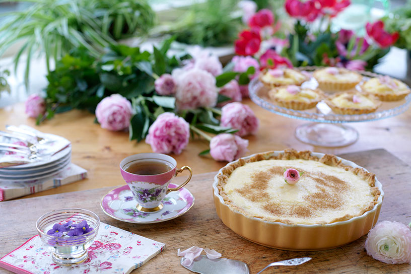 Zoete melktaart gedecoreerd met een roosje en een kopje thee